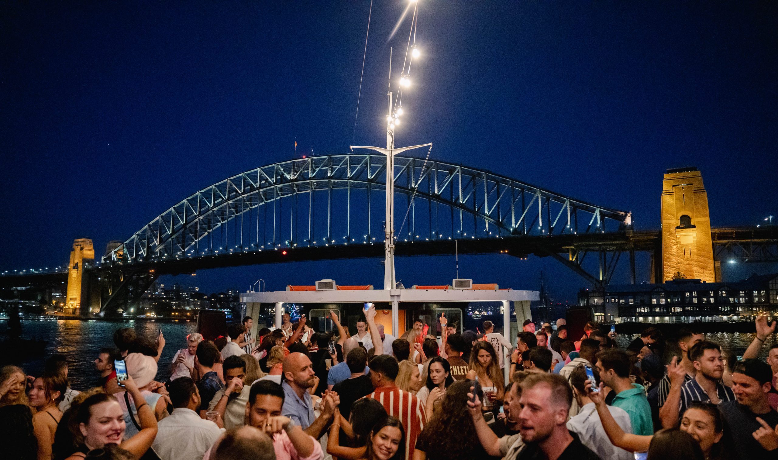 Crowd celebrating beneath Sydney Harbour Bridge at night