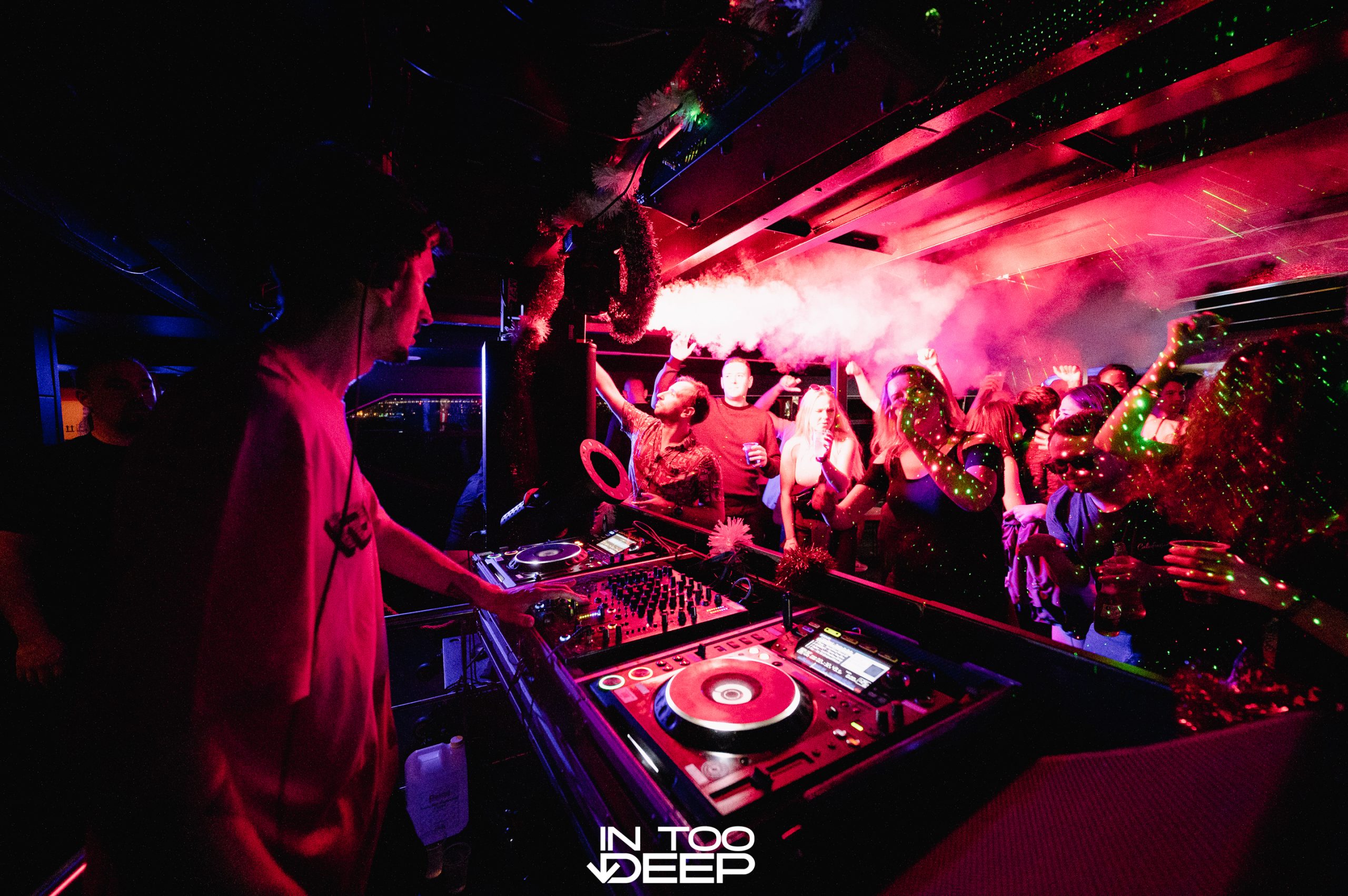 DJ performing beneath pink and purple nightclub lighting