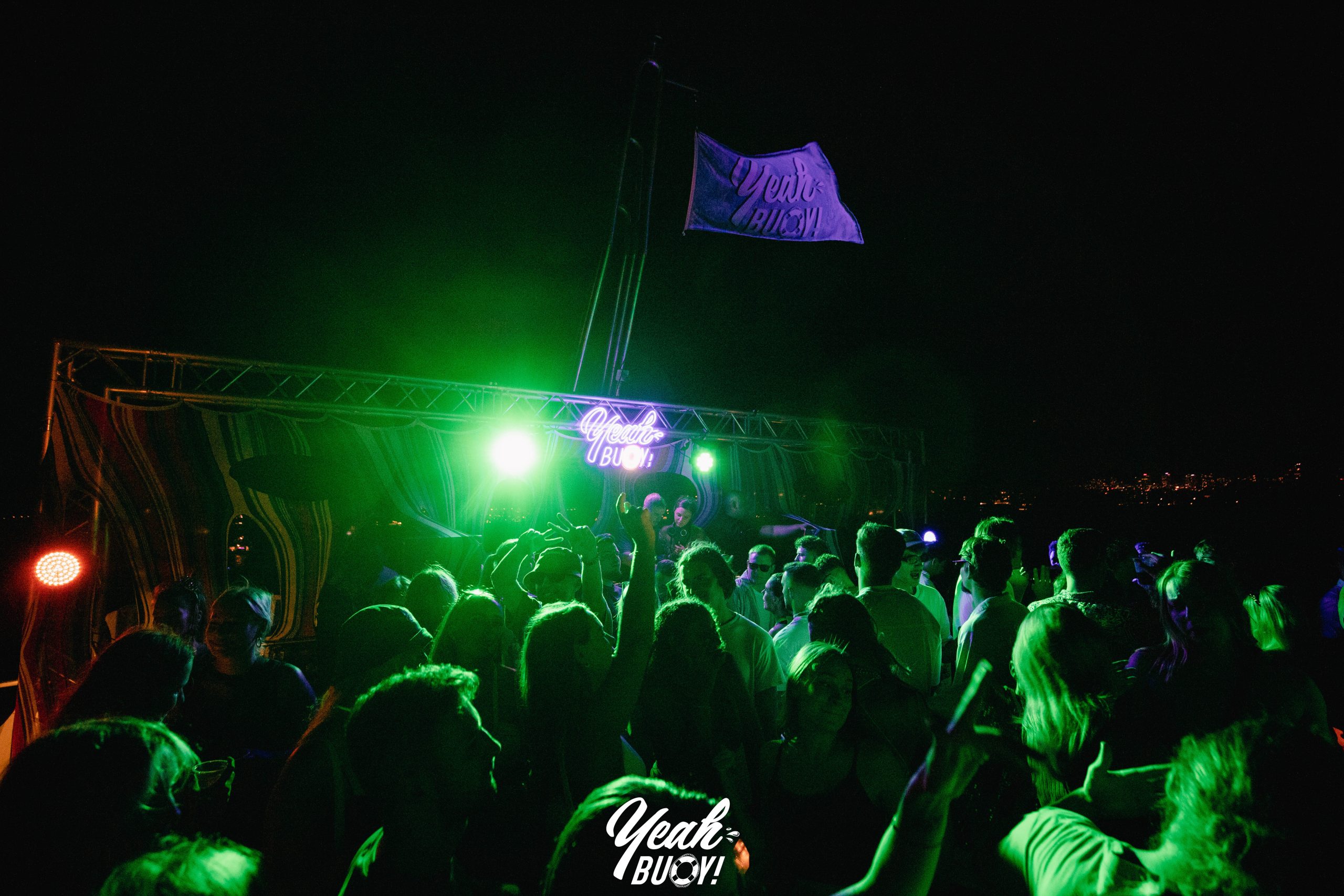 Crowd dancing beneath green lighting at a yacht party