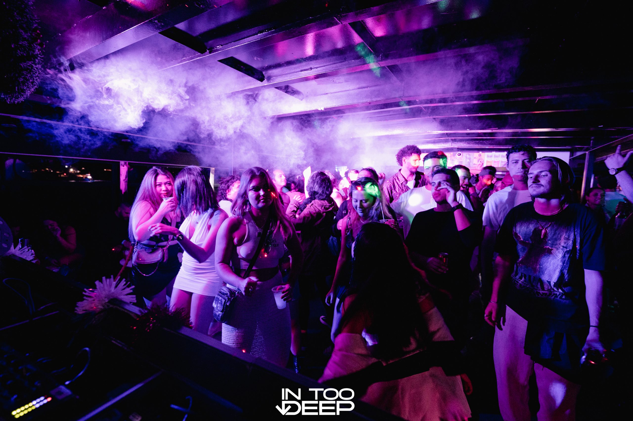 Guests dancing at a purple-lit yacht party