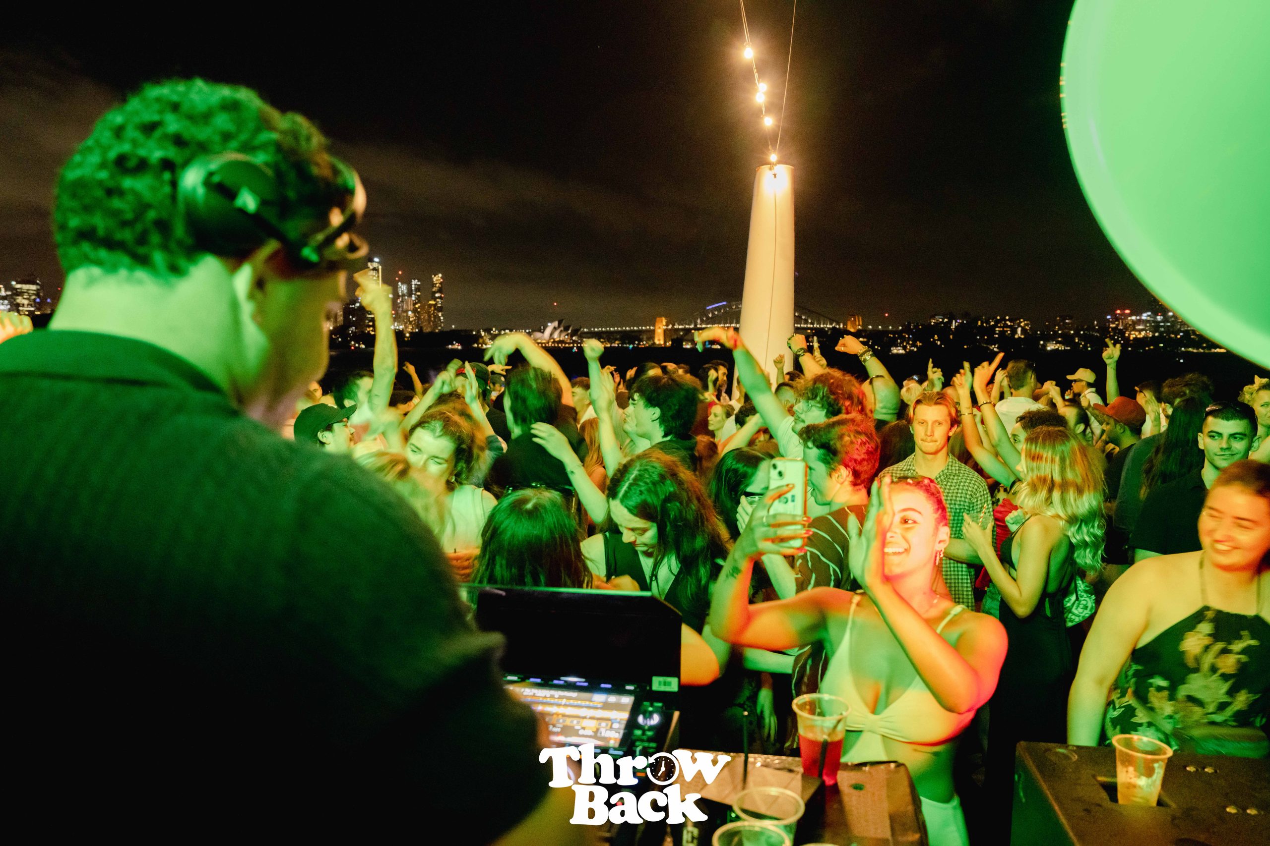Guests dancing beneath green stage lighting onboard
