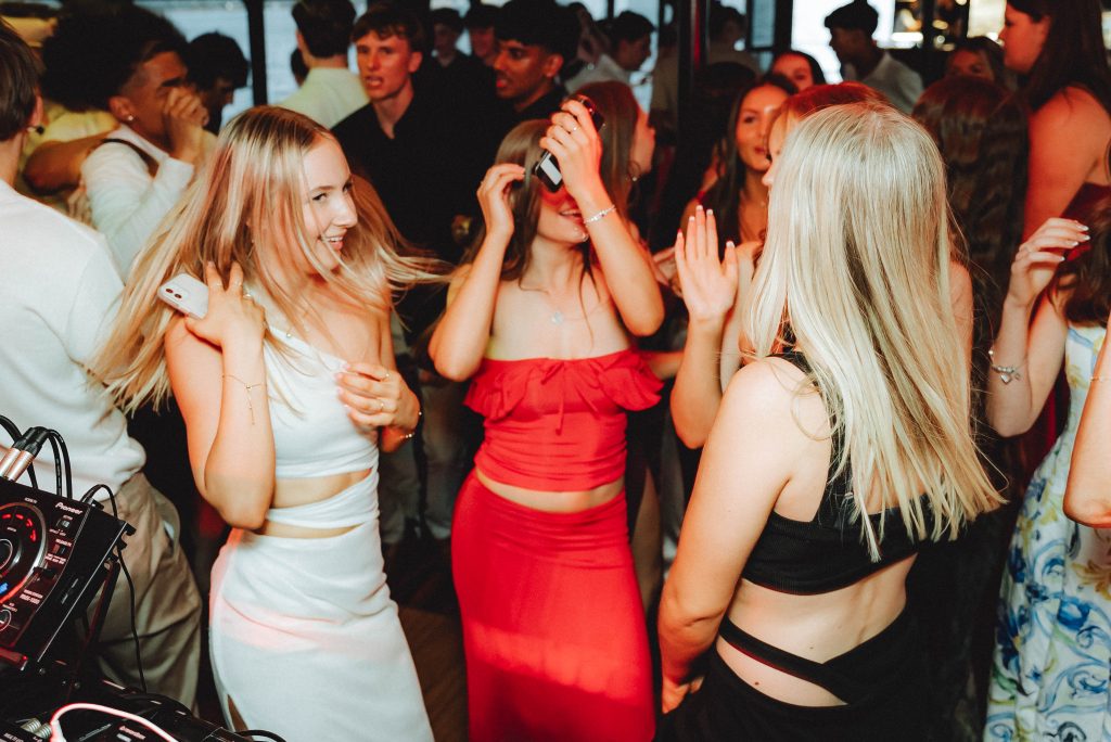 Women dancing beside the DJ booth onboard